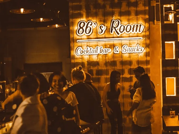 86's Room neon sign at a cocktail bar and snacks venue with patrons outside at night