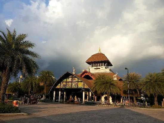 Chiang Mai Night Safari entrance building with thatched dome roof and palm trees under cloudy sky