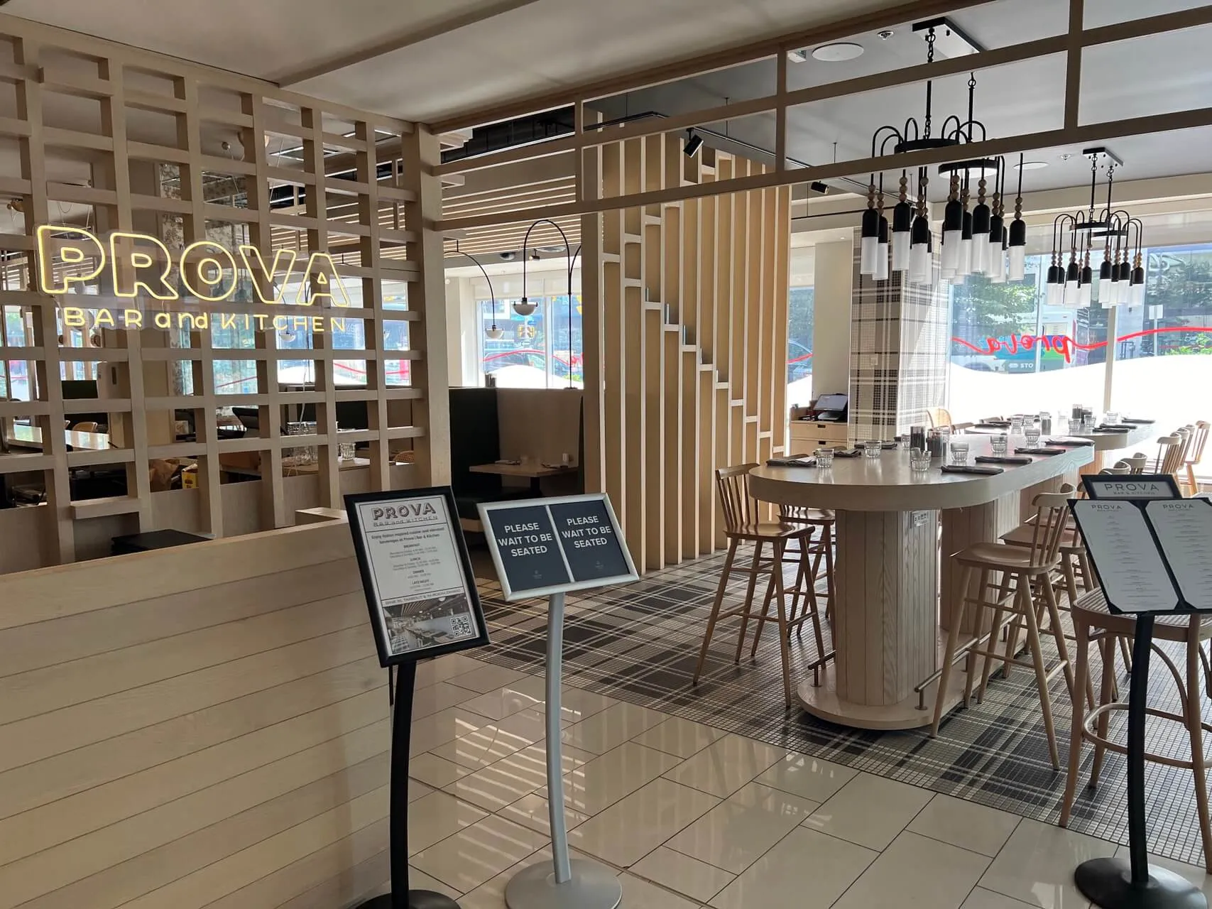 Prova Bar and Kitchen at Delta Hotels Ottawa, featuring open kitchen counter with bar seating and modern geometric wood panel dividers.