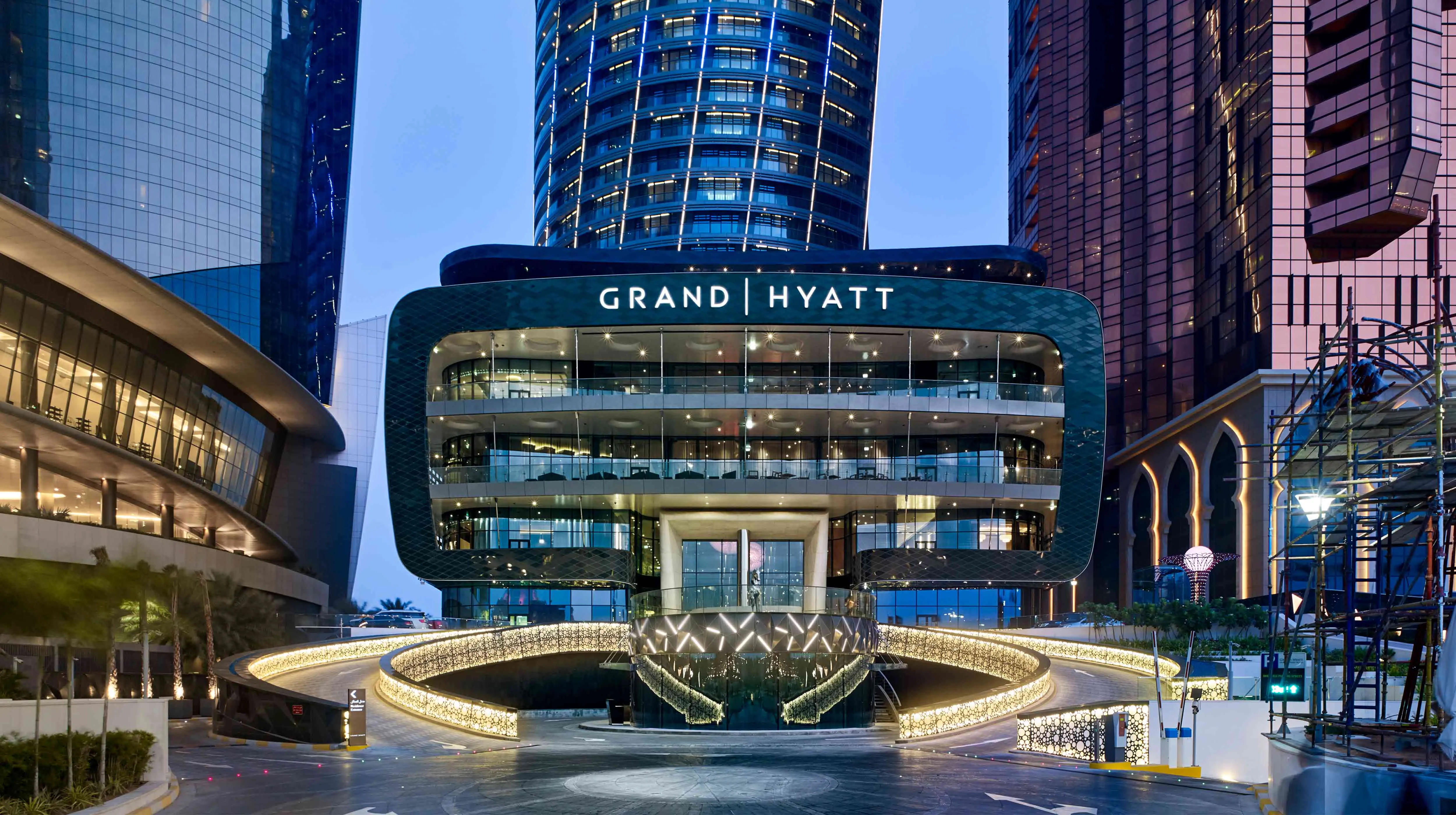 Grand Hyatt Abu Dhabi exterior at dusk with illuminated curved architecture and surrounding high-rise towers