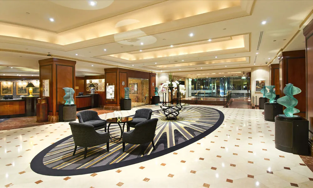 Hilton Park Lane London lobby with geometric floor pattern, modern seating, art displays, and bronze sculptures