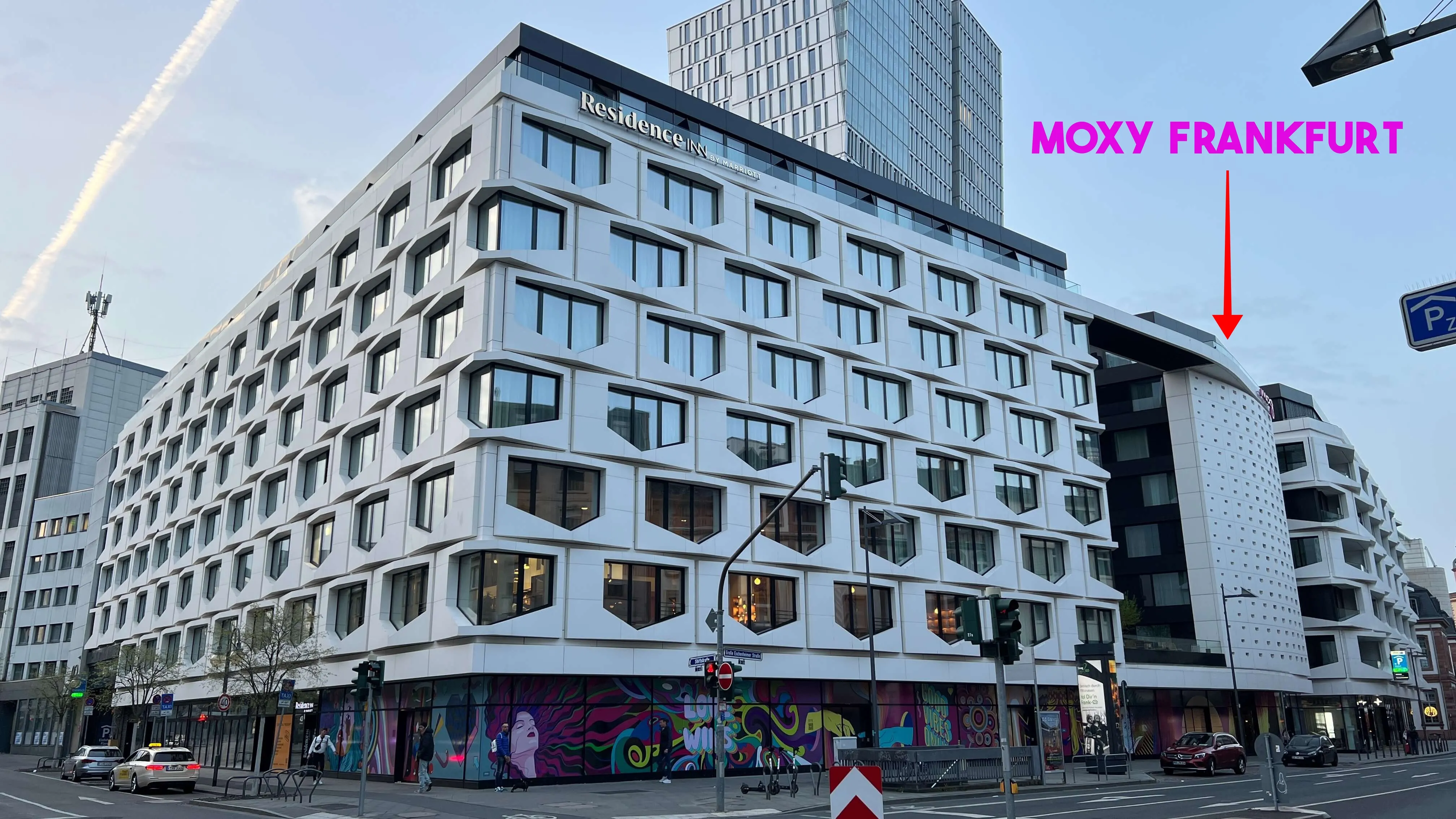Moxy Frankfurt hotel exterior with contemporary architecture, ground-floor retail, and city street setting