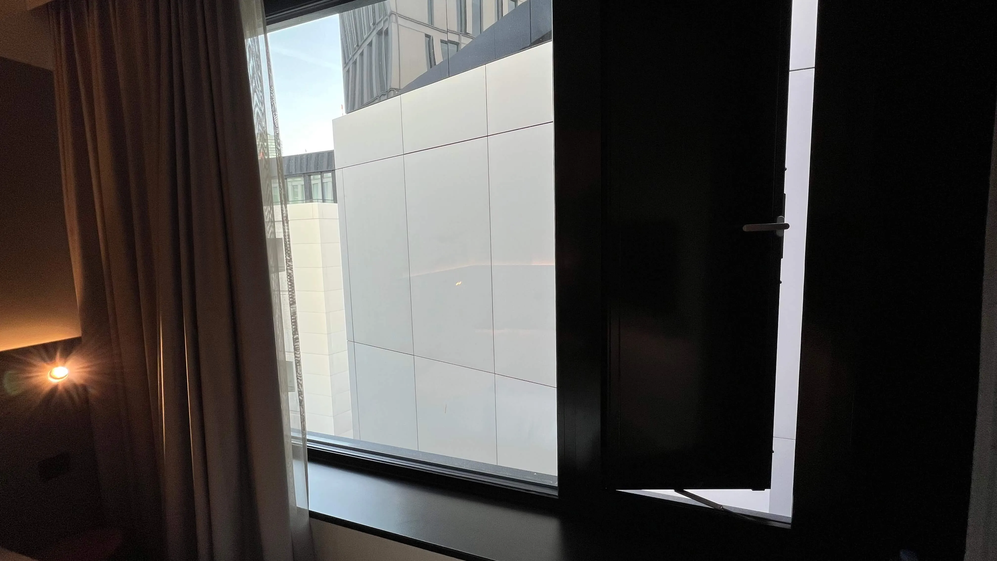 Modern hotel room window with city view and white panel building exterior at Moxy Frankfurt City Center