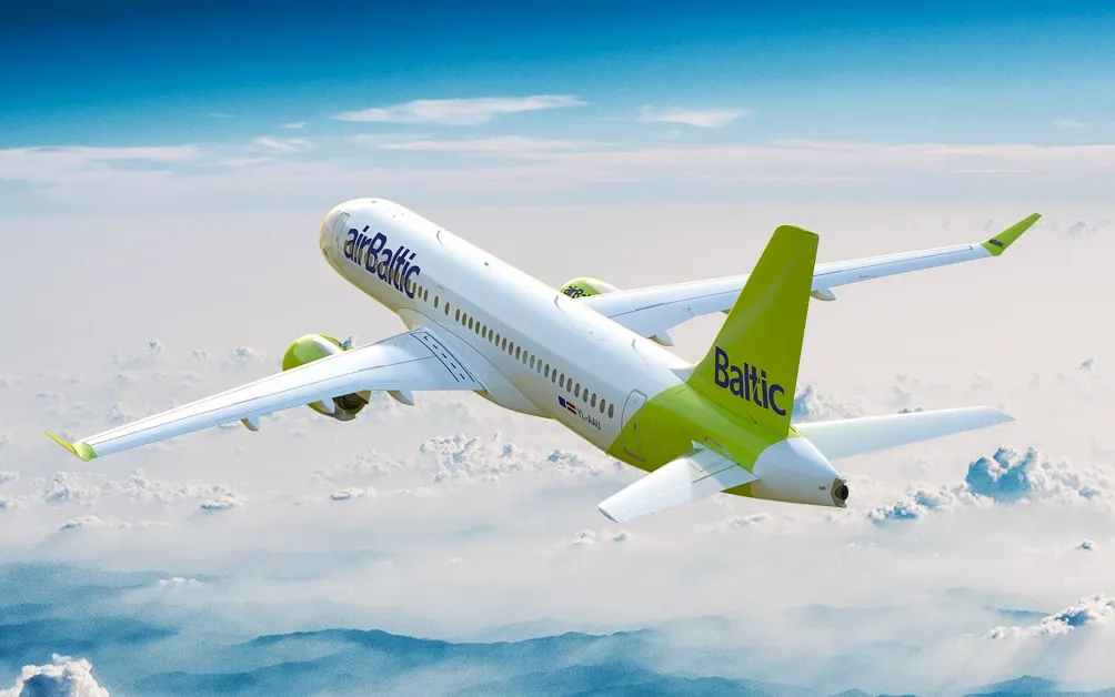 airBaltic Airbus A220 aircraft in flight above clouds with lime green and white livery