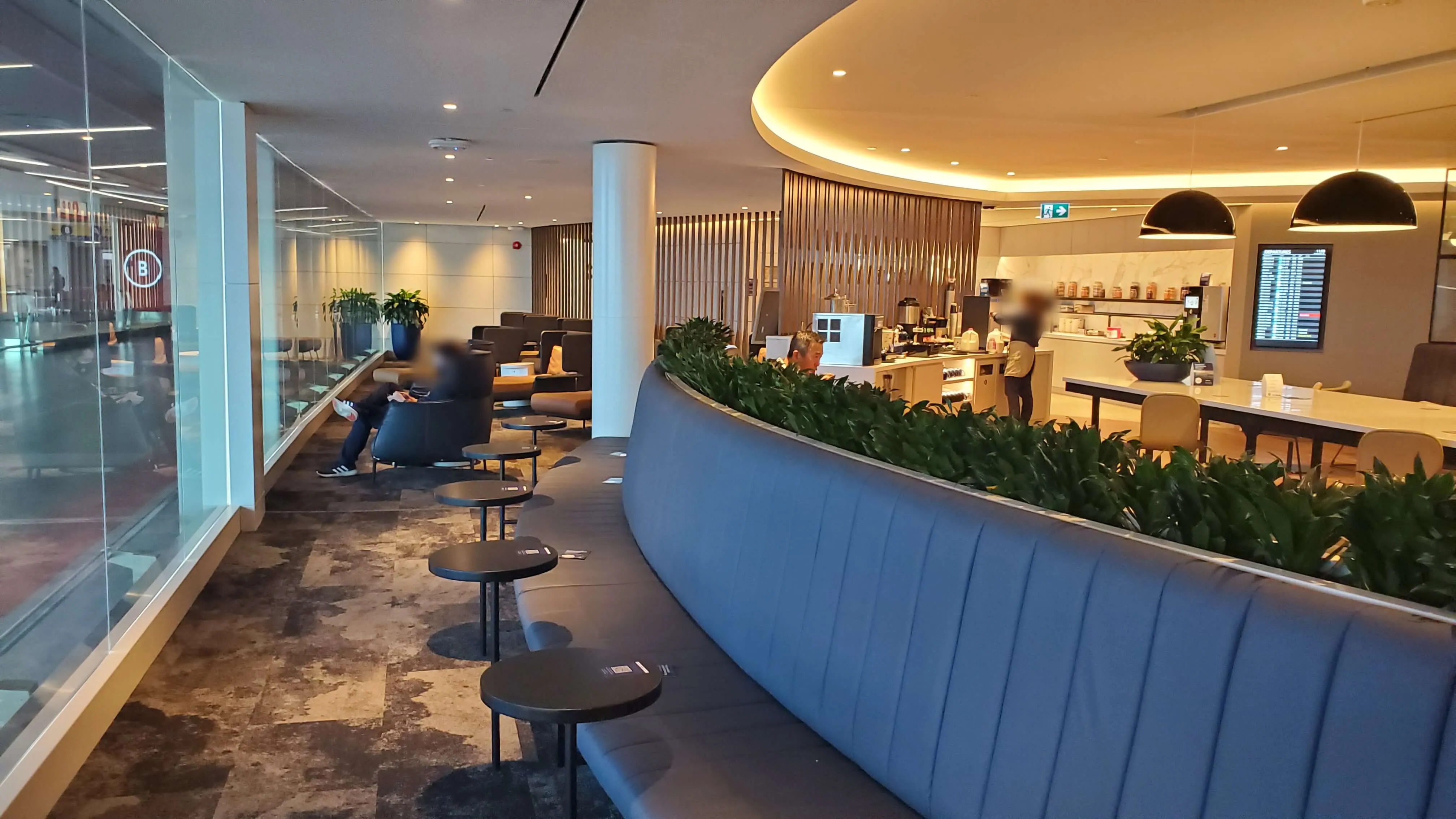 Modern airport lounge with curved seating area, high ceilings, and contemporary furnishings in warm and cool tones