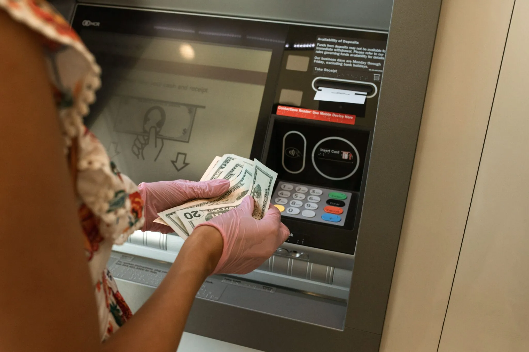 Person counting US twenty-dollar bills withdrawn from an ATM
