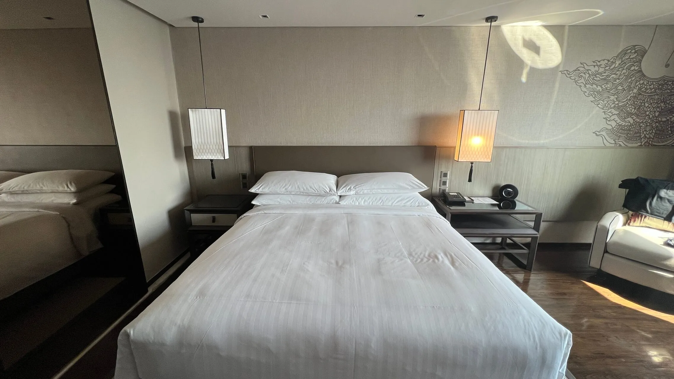 Queen bed with white linens and pendant lighting at the Bangkok Marriott Marquis
