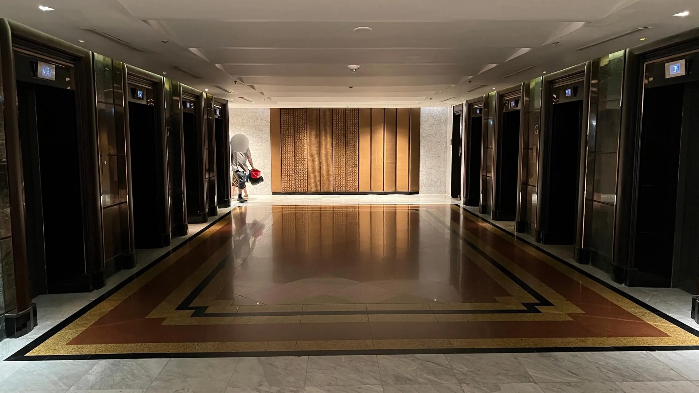 Modern elevator bank with polished marble flooring and wooden accent wall at Bangkok Marriott Marquis.