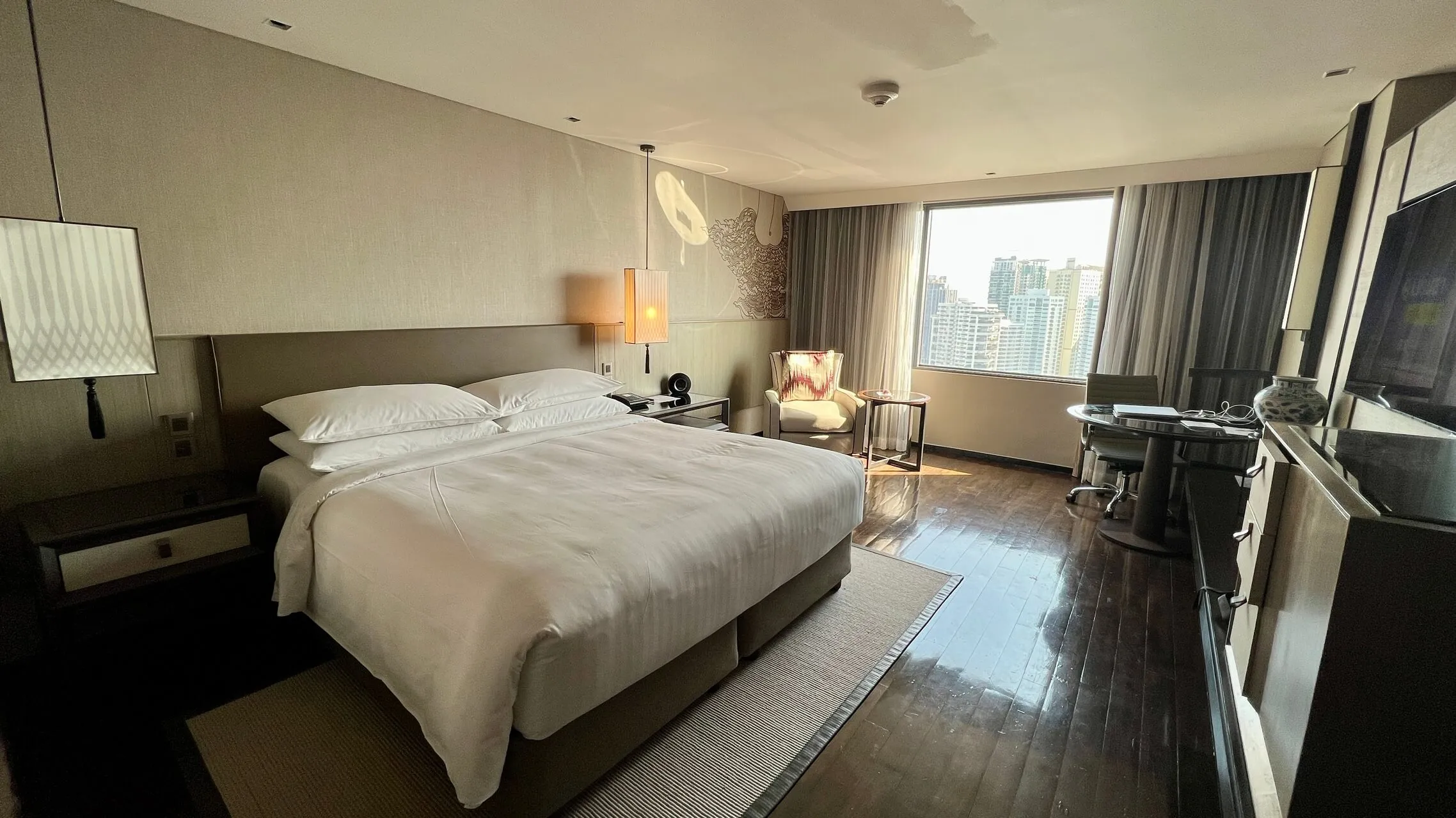 King bed with white linens and city view at Bangkok Marriott Marquis hotel room