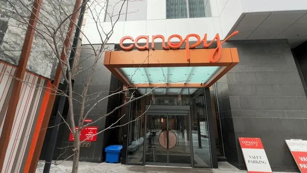 Canopy by Hilton hotel entrance with orange signage and glass facade