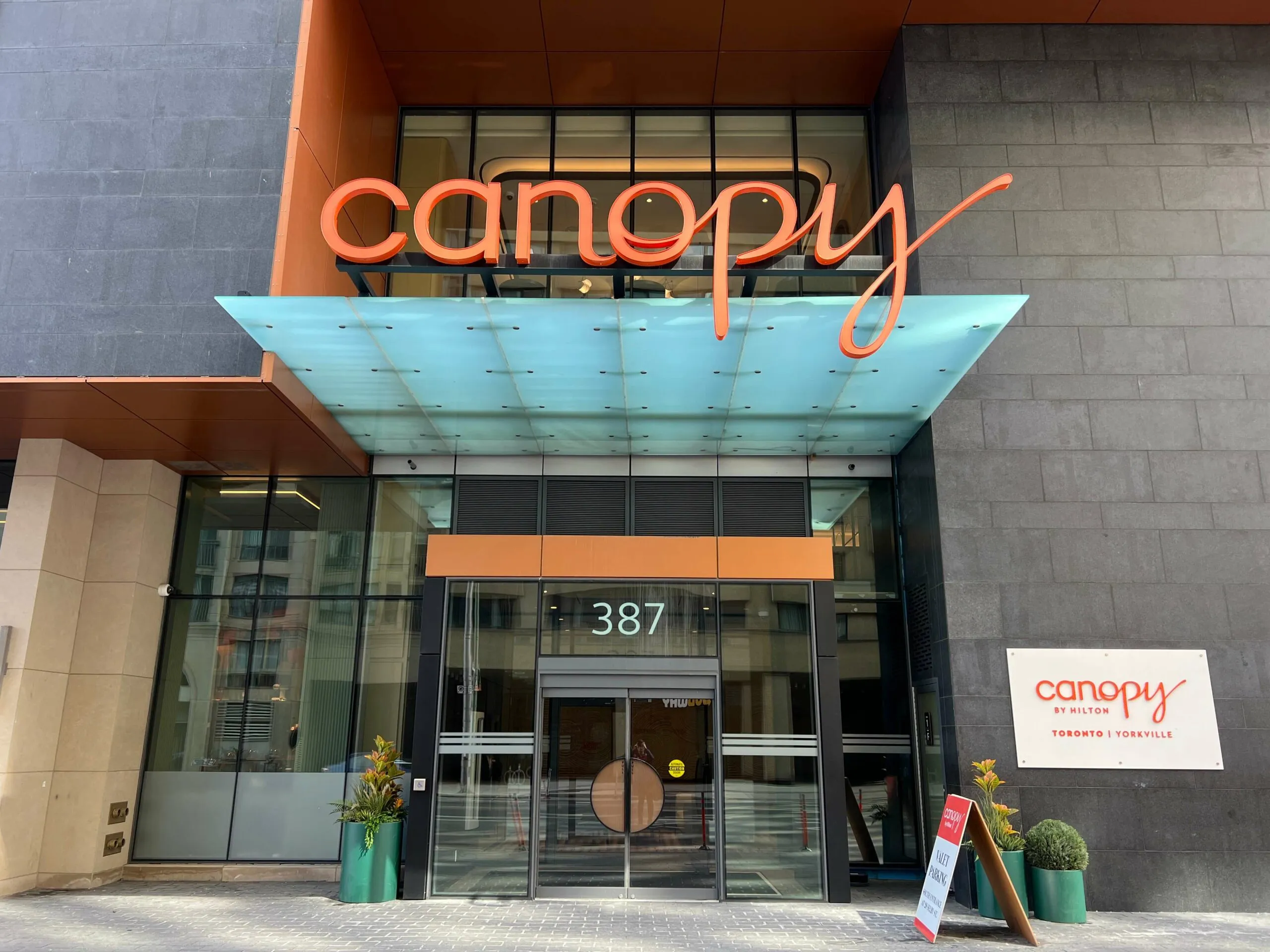Canopy by Hilton storefront with orange neon signage and turquoise awning at 387
