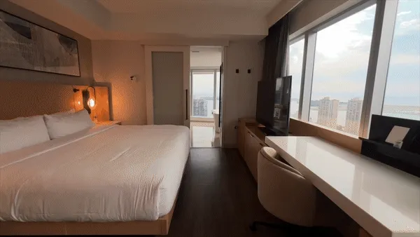 King bed with warm accent lighting and city view from high-rise hotel room at Delta Hotels Toronto