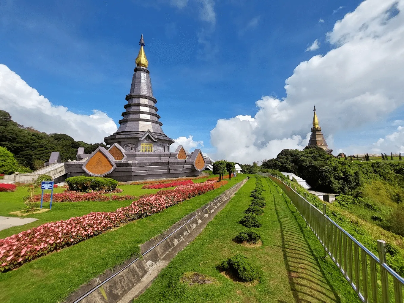 Twin golden-spired pagodas with manicured gardens and red flowers at Doi Inthanon National Park, Thailand