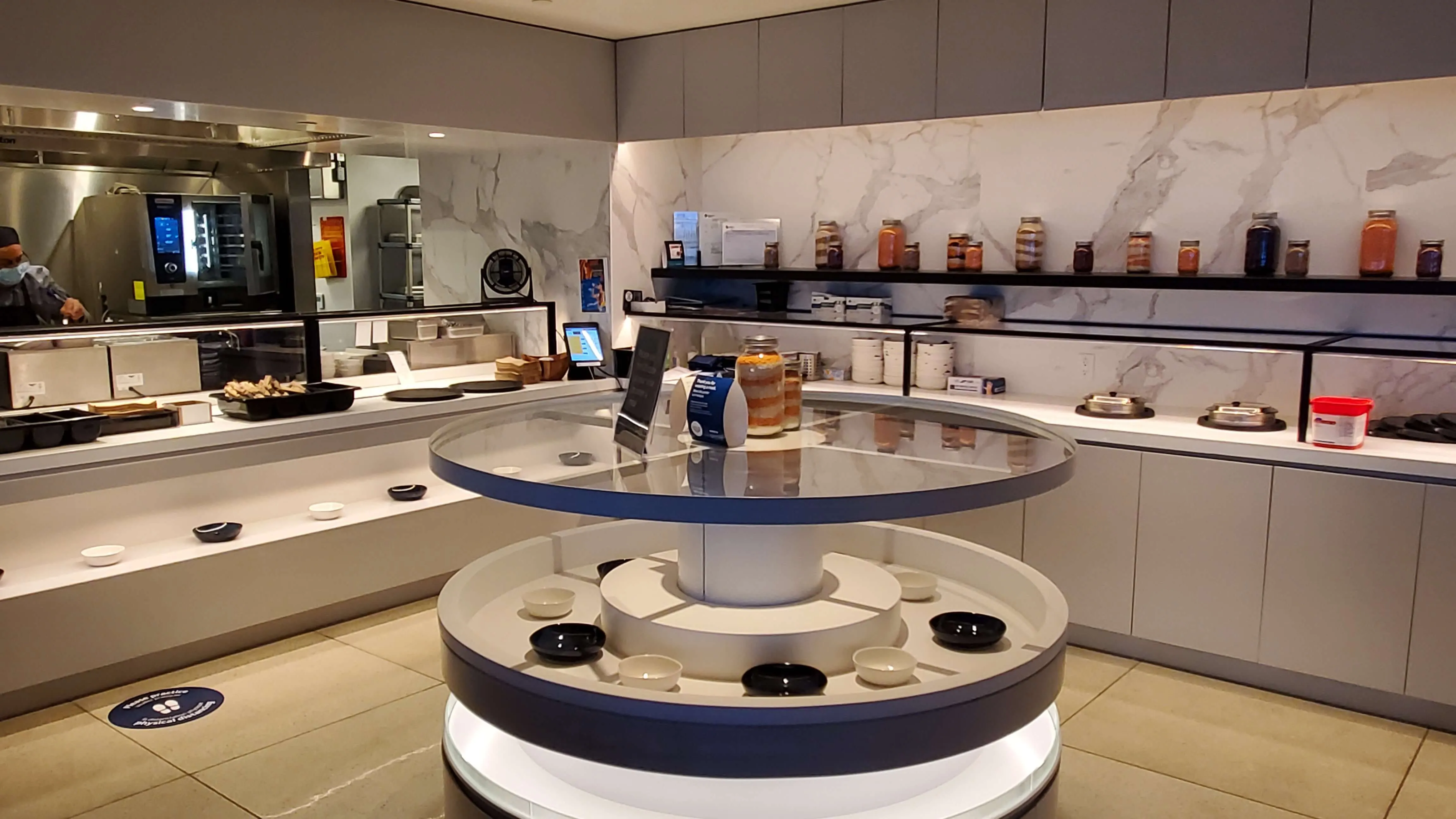 Modern fragrance boutique interior with circular display cases, marble walls, and rows of bottled scents on shelves.