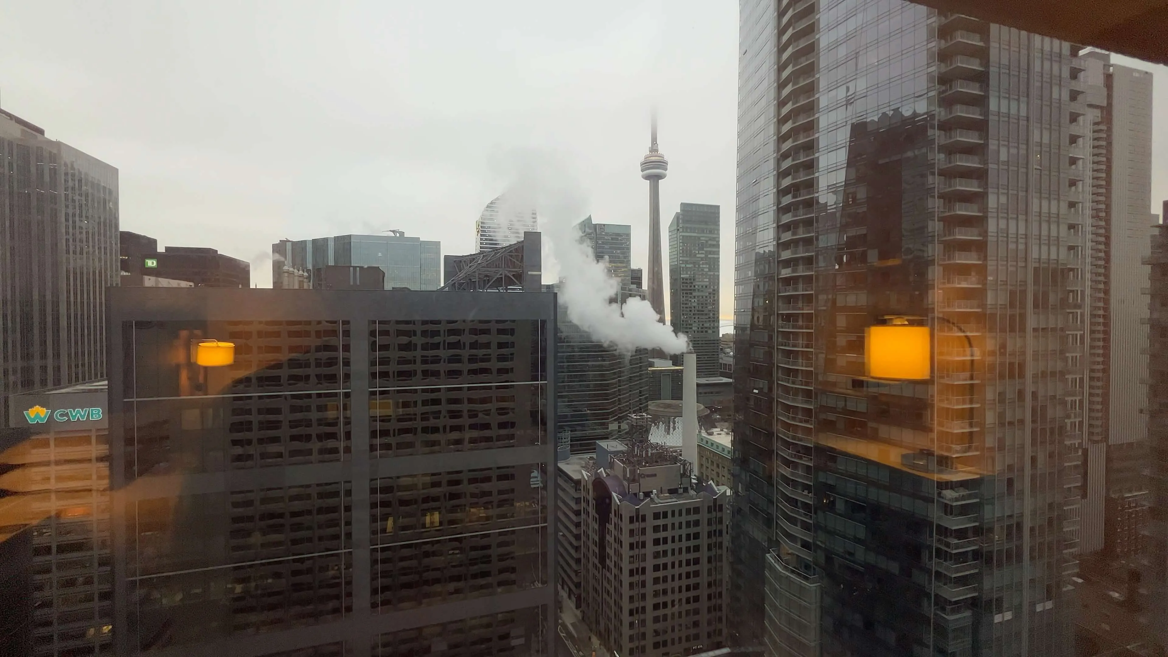 Toronto skyline viewed from hotel window showing CN Tower and downtown core with steam rising from building