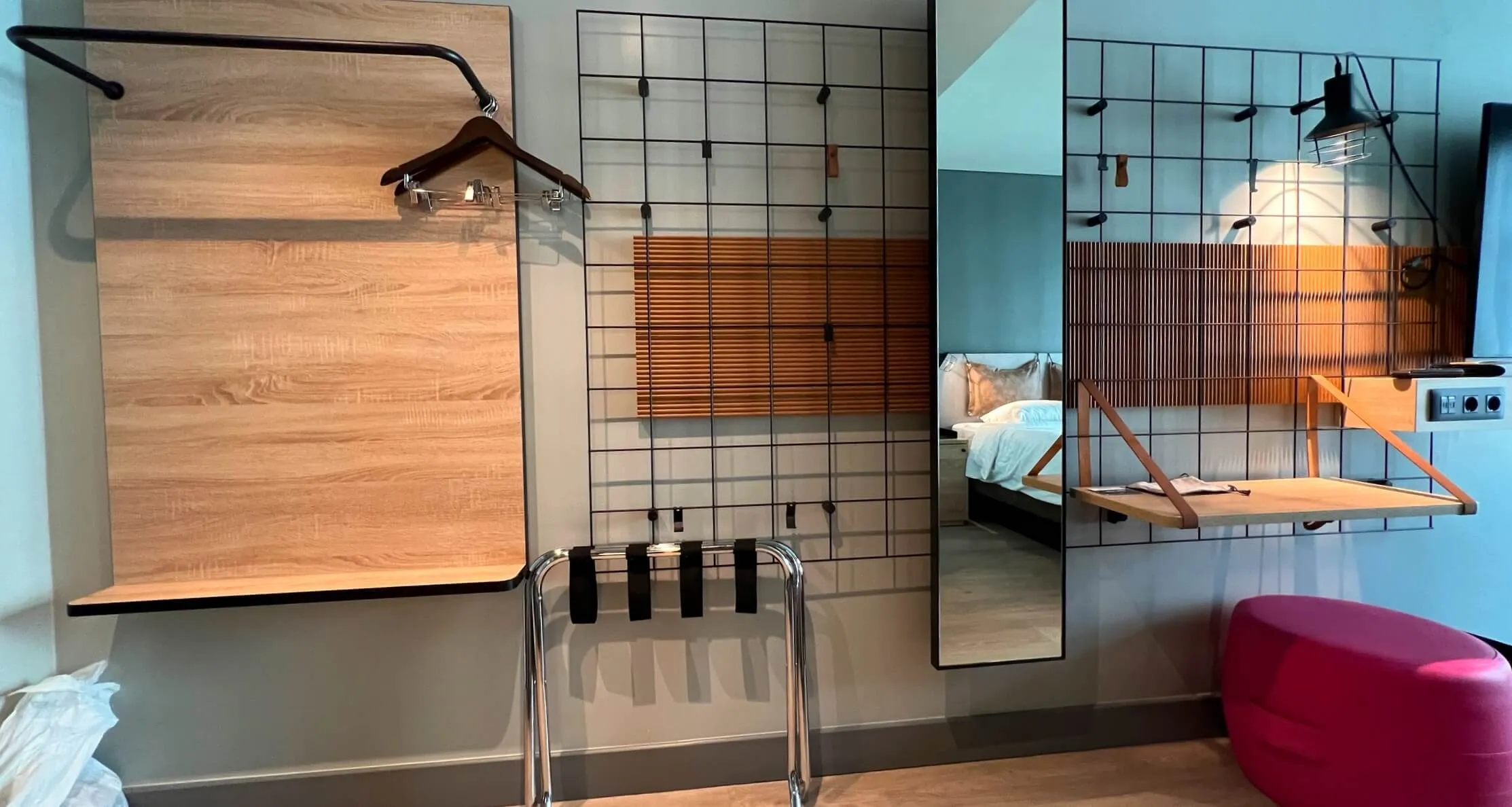 Hotel room display showcasing shower enclosure with wood paneling, bed with industrial frame, and modern minimalist design elements.