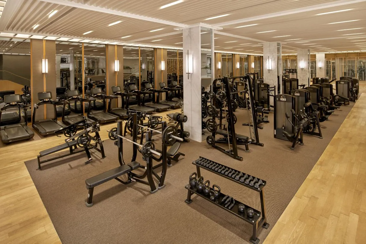 Fitness center with cardio and strength equipment, mirrored walls, and wooden ceiling at JW Marriott Dubai Downtown.