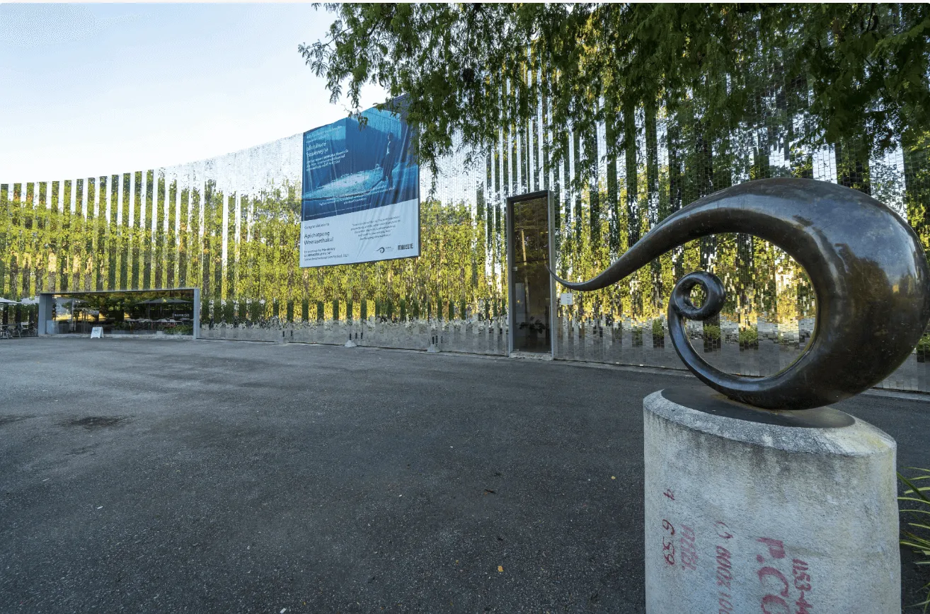 Modern sculpture and entrance to Mailam contemporary art museum with striped fence and birch trees