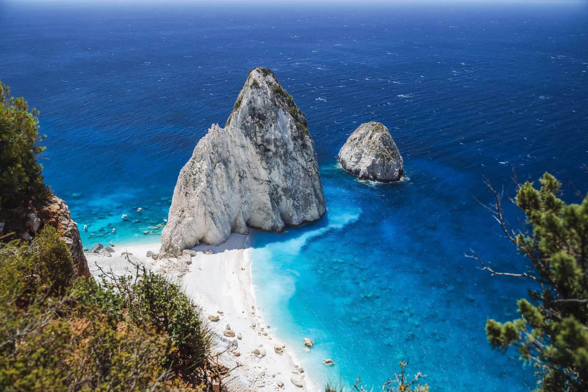 Navagio Beach with dramatic white limestone rock formations rising from turquoise water and white sand, Zakynthos Greece
