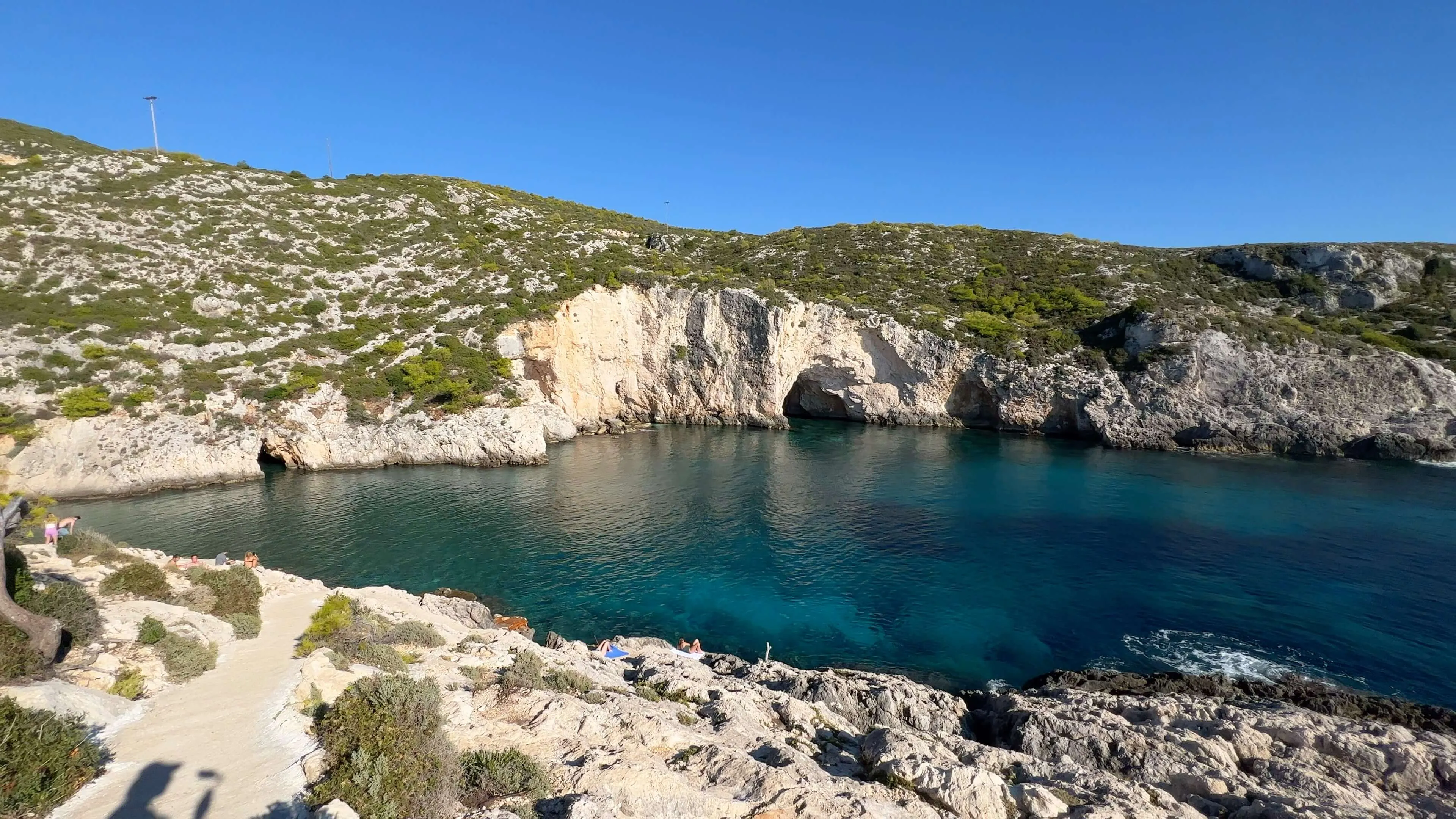 Turquoise cove with limestone cliffs and sea cave at Port Limnionas, Mediterranean.