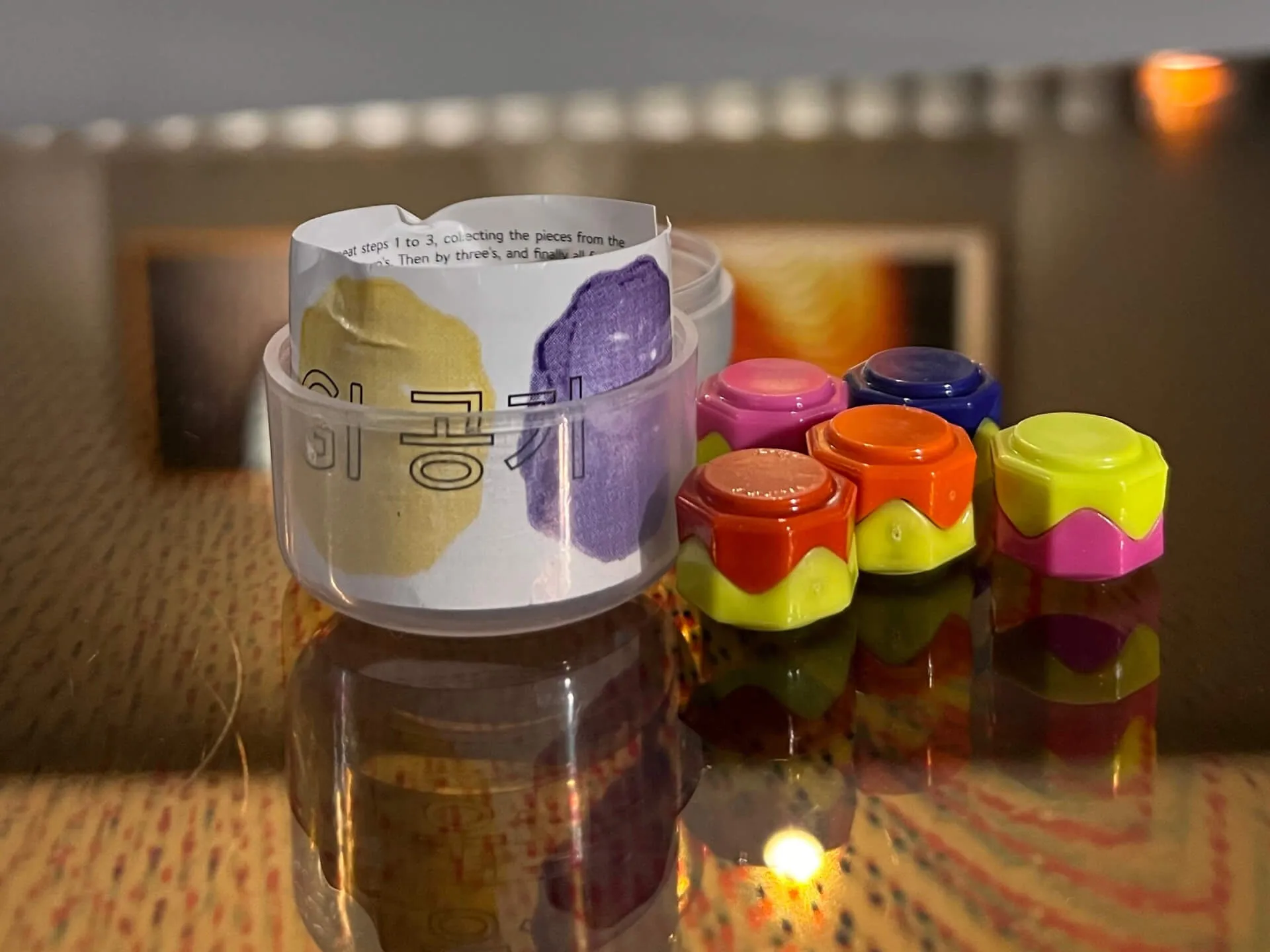 Gongginori Korean game pieces and instruction cylinder on a hotel room table with warm lighting