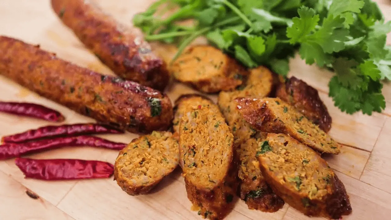 Sai oua (Northern Thai sausage) sliced with roasted potatoes, purple long beans, and fresh cilantro on a wooden board