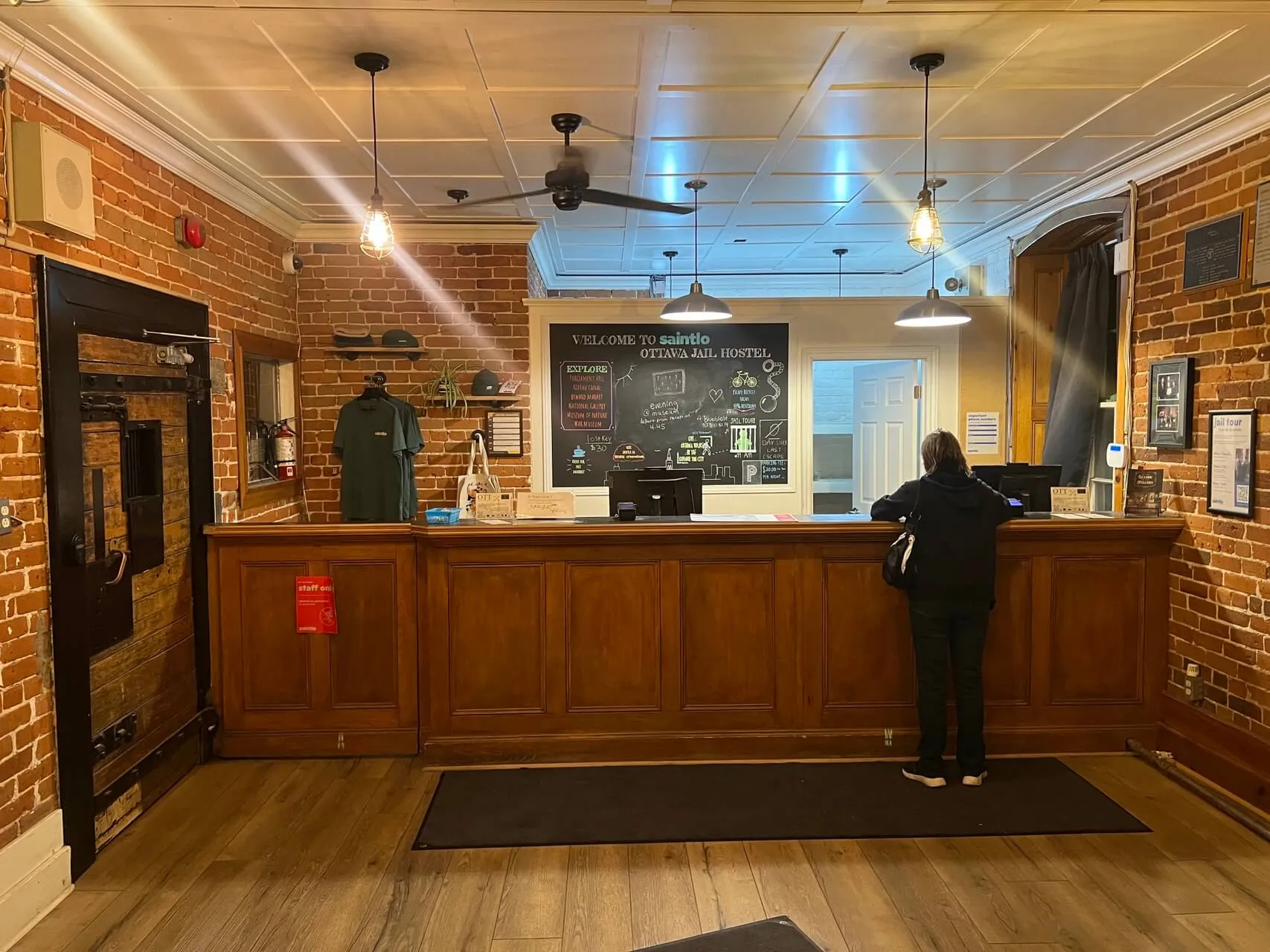 Lobby reception desk at Saint-Louis hotel in Ottawa, with exposed brick, wood paneling, and chalkboard menu behind desk.