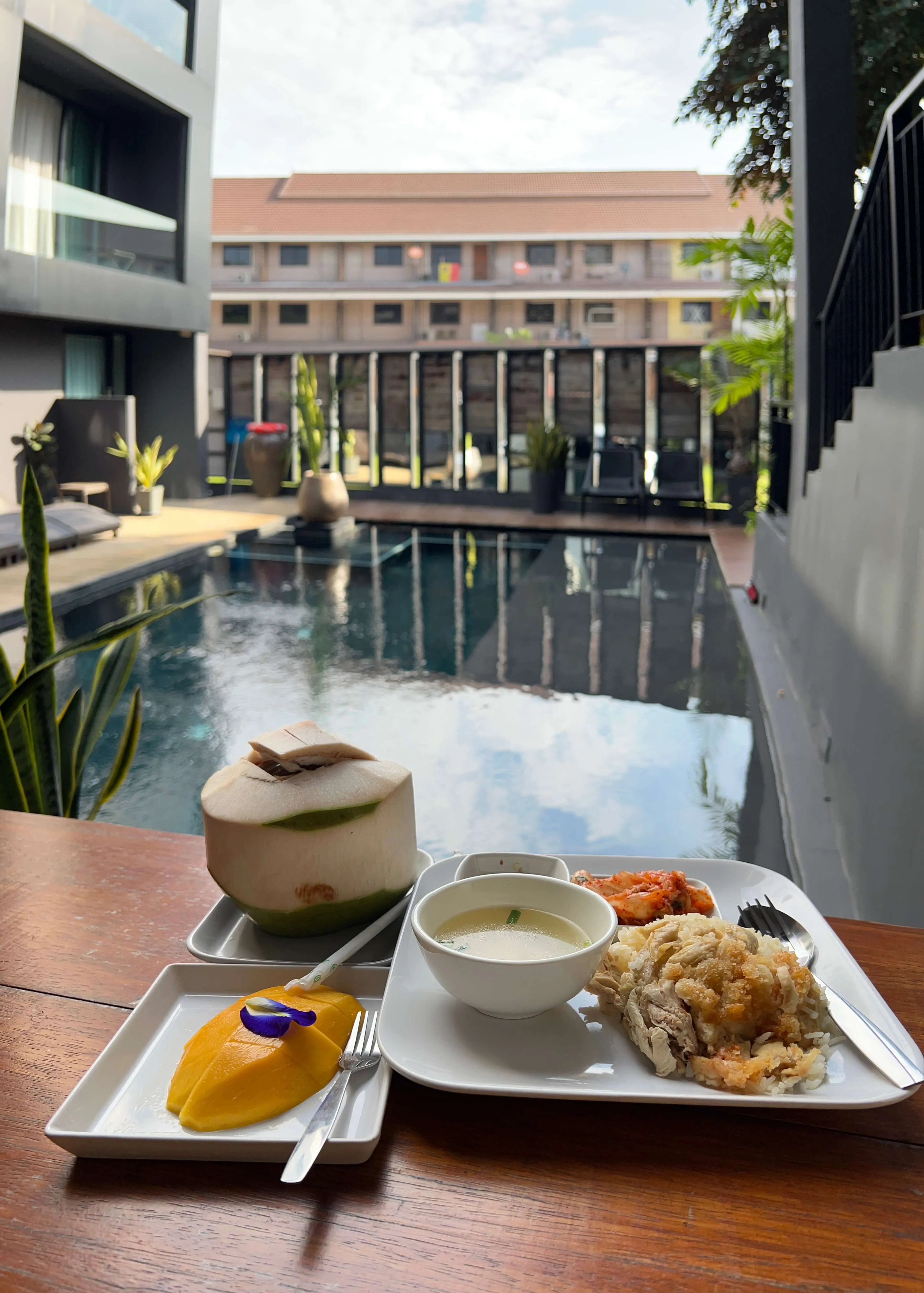 Modern hotel courtyard with reflecting pool, contemporary architecture, and plated Asian cuisine in foreground