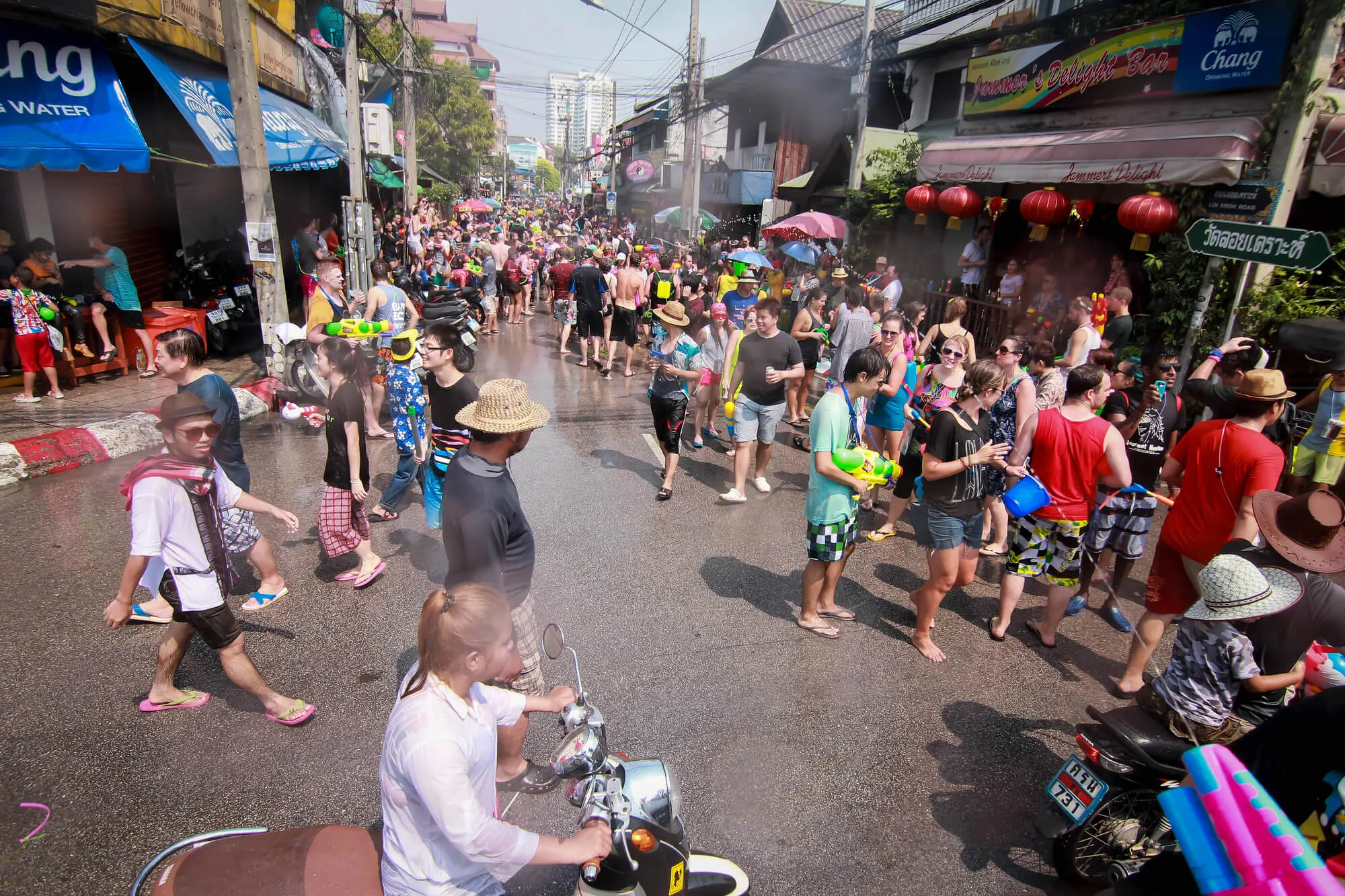 Crowded street during Songkran water festival with residents and tourists holding water guns and buckets