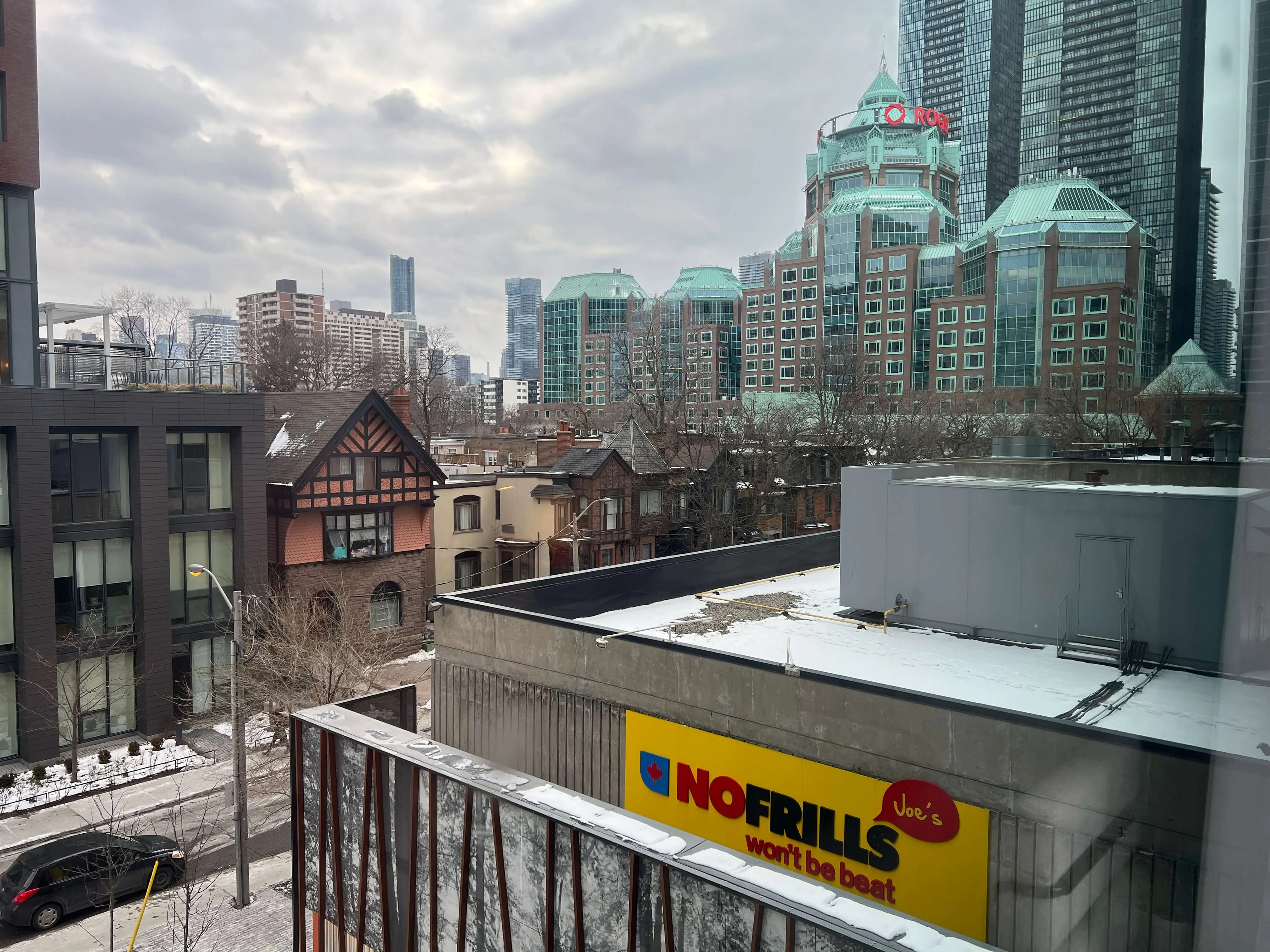 Toronto skyline with distinctive copper-roofed buildings and historic rowhouses in foreground, Norfills sign visible on adjacent structure