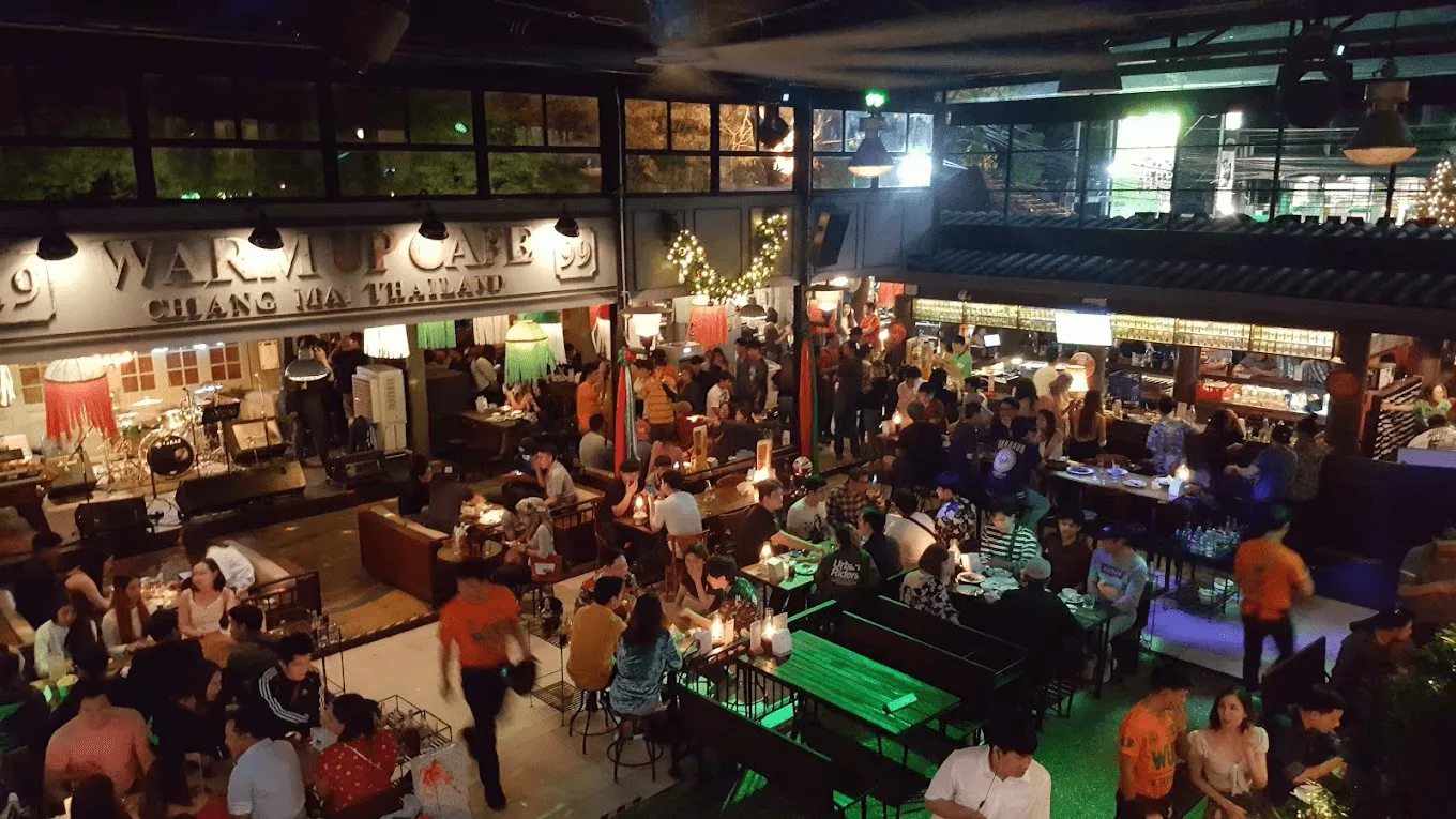 Busy night market or food hall with multiple vendor stalls, crowds, and warm lighting in Bangkok, Thailand