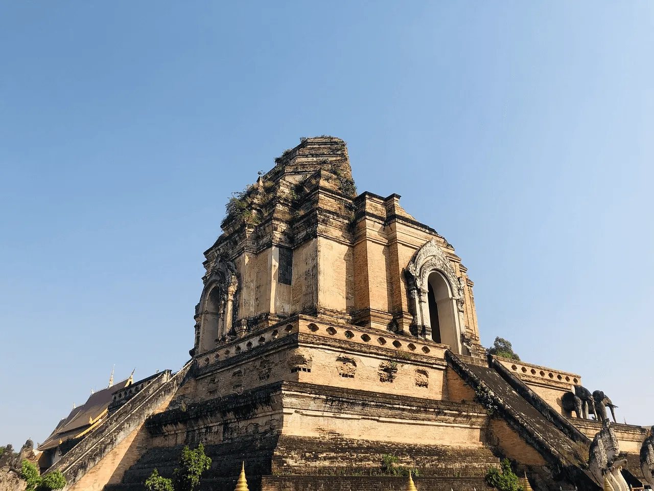 Wat Chedi Luang ancient brick chedi with ornate carvings against clear blue sky in Chiang Mai