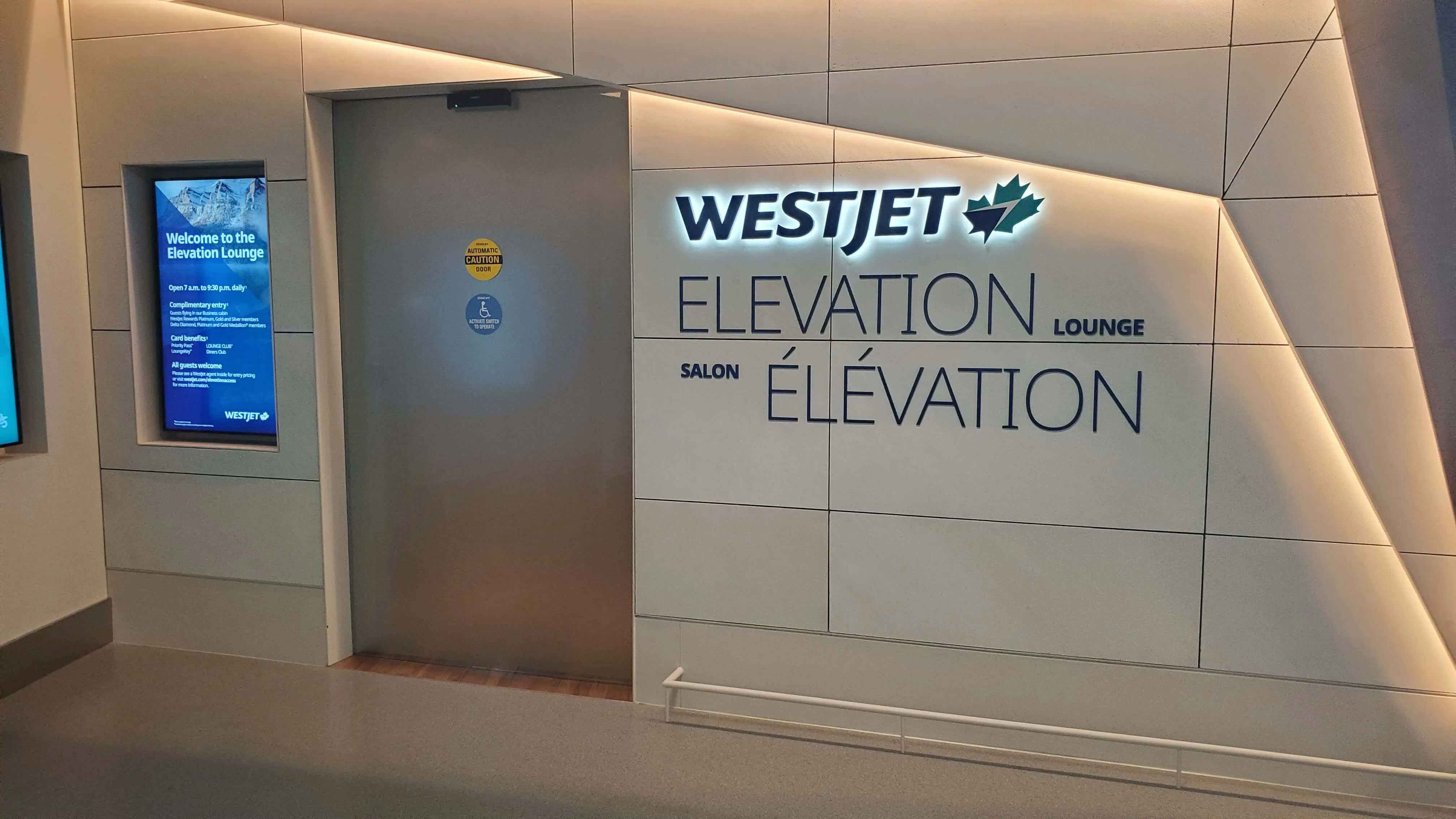 WestJet Elevation Lounge entrance with signage and welcome display in modern minimalist hallway