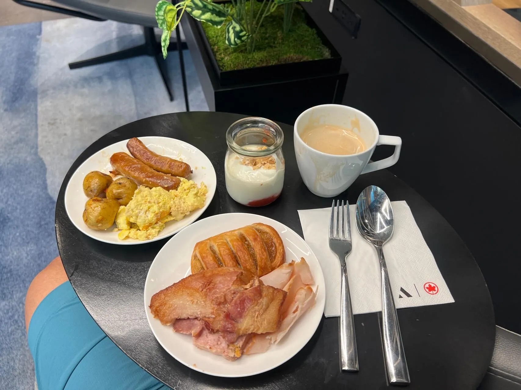 Air Canada Aspire Lounge breakfast with scrambled eggs, sausage, bacon, croissant, potatoes, yogurt, and coffee